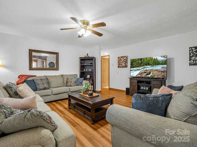 living room featuring a textured ceiling, ceiling fan, and light wood-type flooring