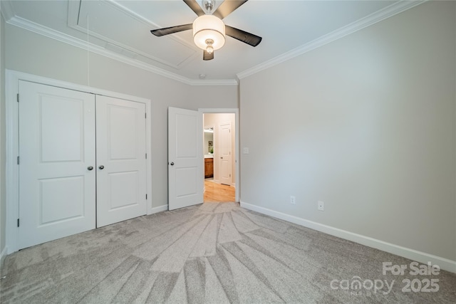 unfurnished bedroom with crown molding, light colored carpet, ceiling fan, and a closet