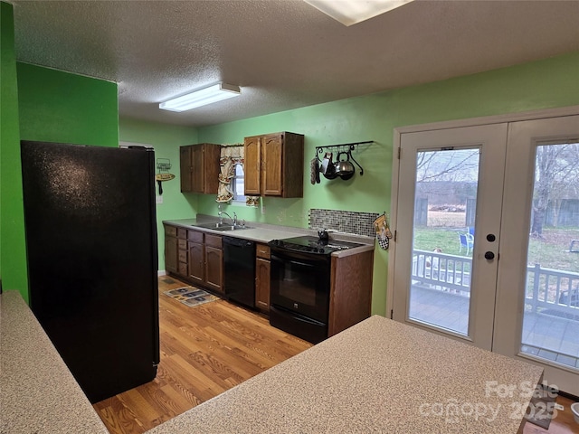 kitchen featuring french doors, sink, a textured ceiling, light wood-type flooring, and black appliances