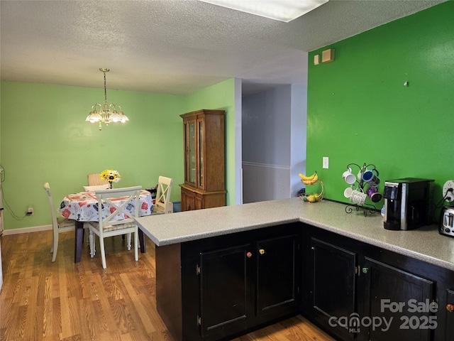 kitchen featuring decorative light fixtures, a chandelier, light hardwood / wood-style floors, and kitchen peninsula