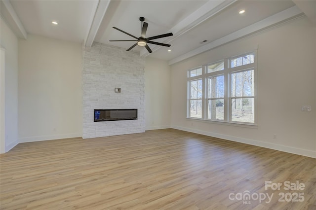 unfurnished living room featuring beamed ceiling, ceiling fan, a fireplace, and light hardwood / wood-style floors