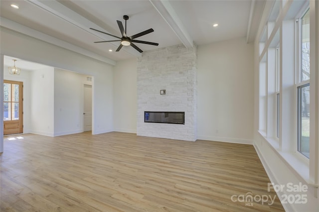 unfurnished living room with beam ceiling, a fireplace, light hardwood / wood-style floors, and ceiling fan with notable chandelier