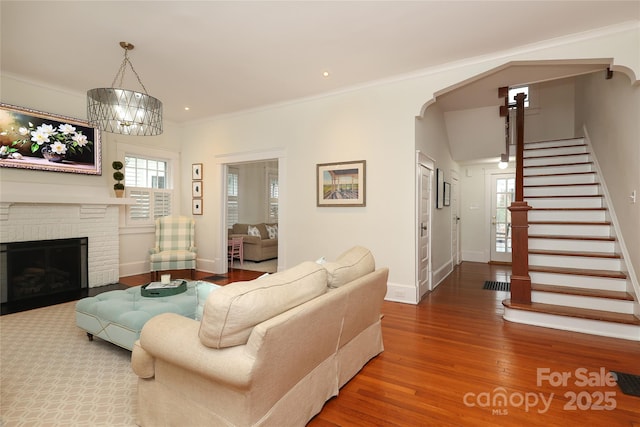 living room featuring crown molding, a chandelier, hardwood / wood-style floors, and a fireplace