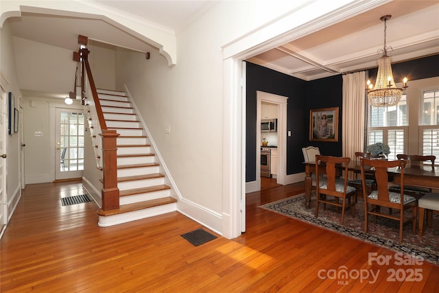 dining room with coffered ceiling, hardwood / wood-style floors, and a notable chandelier