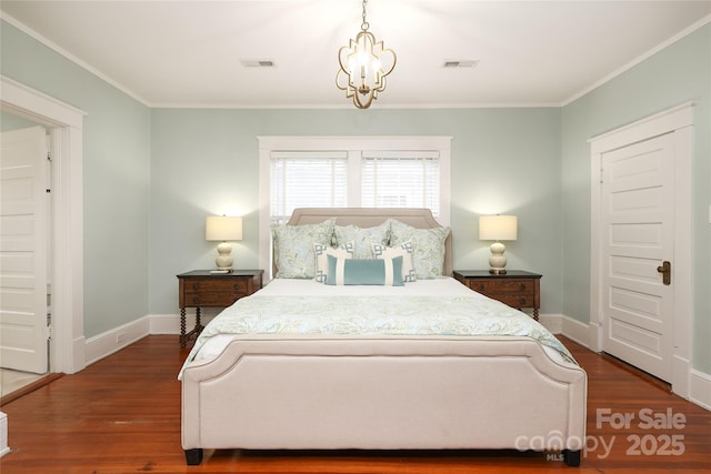 bedroom featuring dark hardwood / wood-style flooring, ornamental molding, and a chandelier