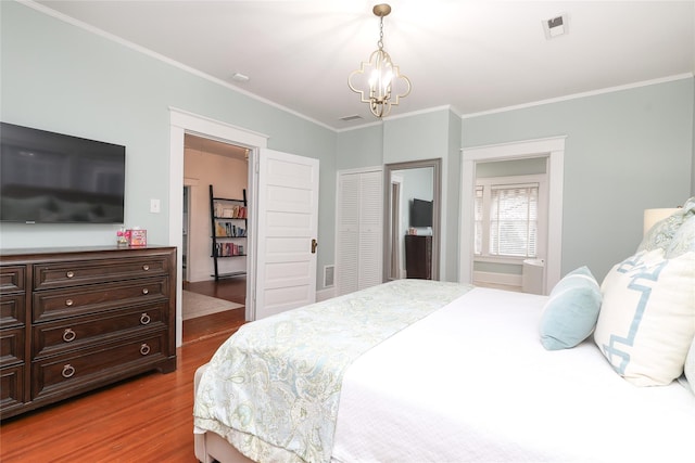 bedroom featuring crown molding, hardwood / wood-style floors, a chandelier, and a closet