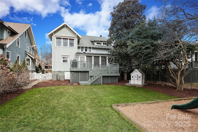 rear view of property with a sunroom, a deck, and a lawn