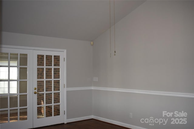 spare room with lofted ceiling, dark wood-type flooring, and french doors