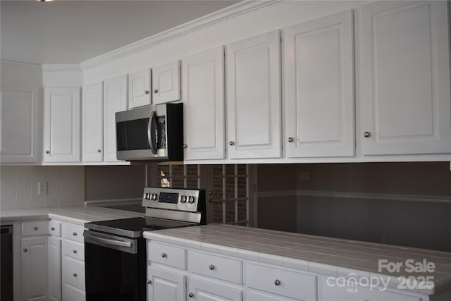 kitchen featuring appliances with stainless steel finishes, tile countertops, white cabinets, and decorative backsplash