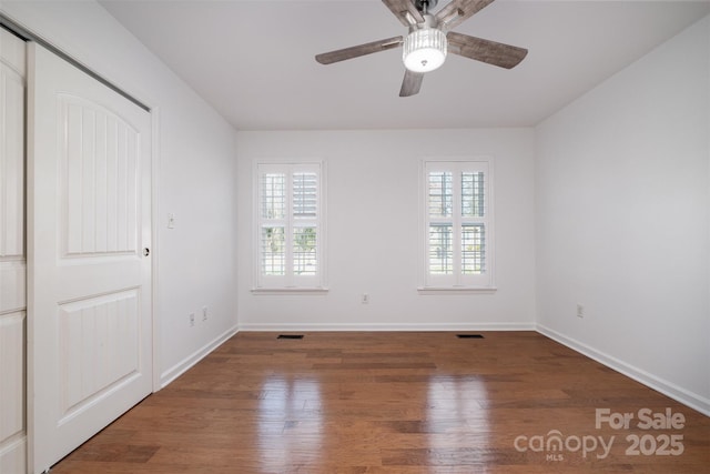 spare room featuring wood finished floors, a wealth of natural light, and baseboards