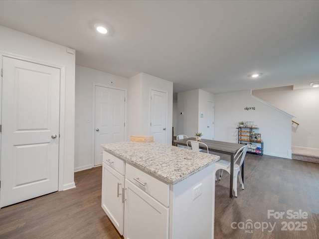 kitchen featuring light stone counters, dark hardwood / wood-style floors, a kitchen island, and white cabinets