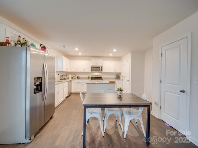 kitchen with light hardwood / wood-style flooring, stainless steel appliances, a center island, and white cabinets