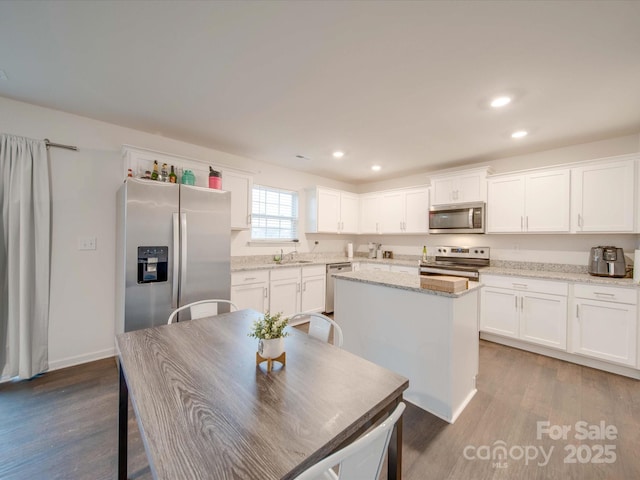 kitchen featuring white cabinetry, appliances with stainless steel finishes, light stone countertops, and a kitchen island