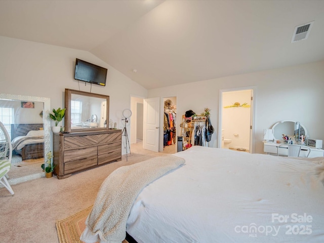 carpeted bedroom with connected bathroom, a walk in closet, a closet, and vaulted ceiling