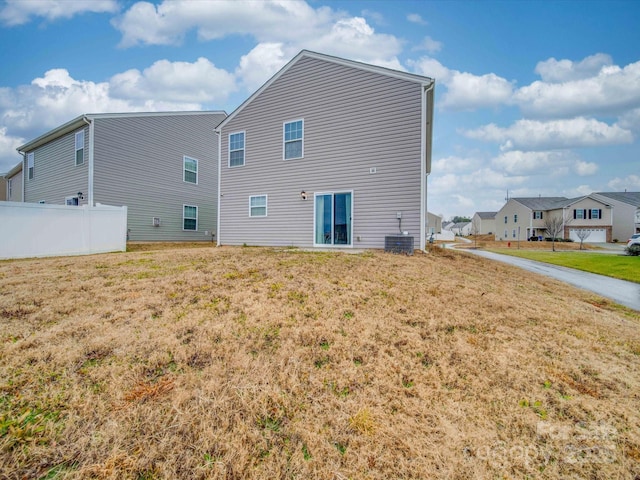 back of property with central AC and a lawn