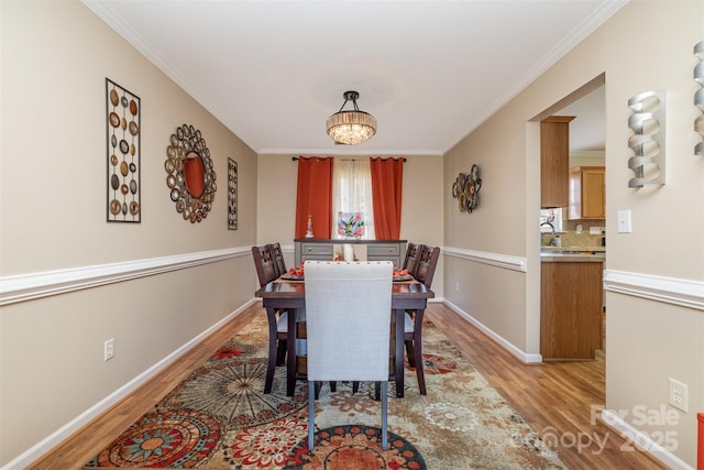 dining room with a notable chandelier, ornamental molding, and light hardwood / wood-style floors