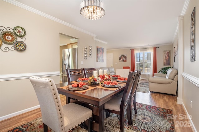 dining space featuring crown molding, light hardwood / wood-style floors, and a notable chandelier