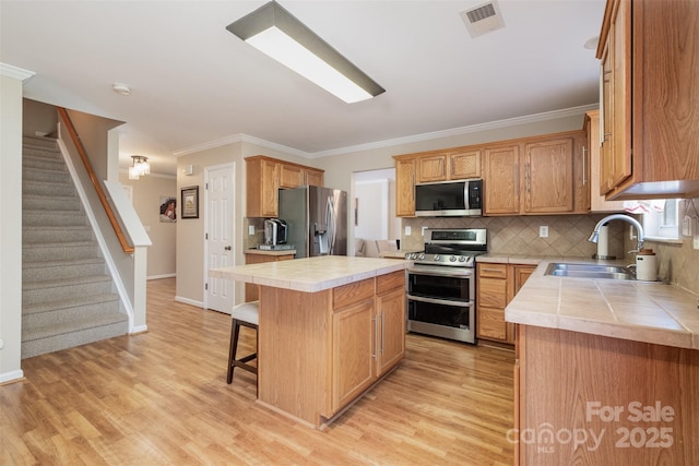 kitchen featuring a kitchen island, appliances with stainless steel finishes, tile countertops, sink, and a kitchen breakfast bar