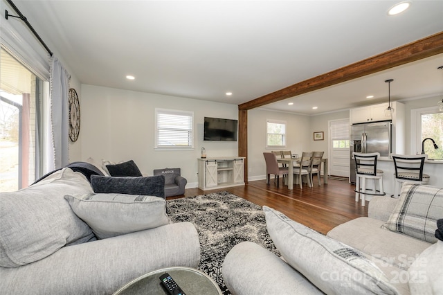 living room with plenty of natural light, dark wood-type flooring, sink, and beam ceiling