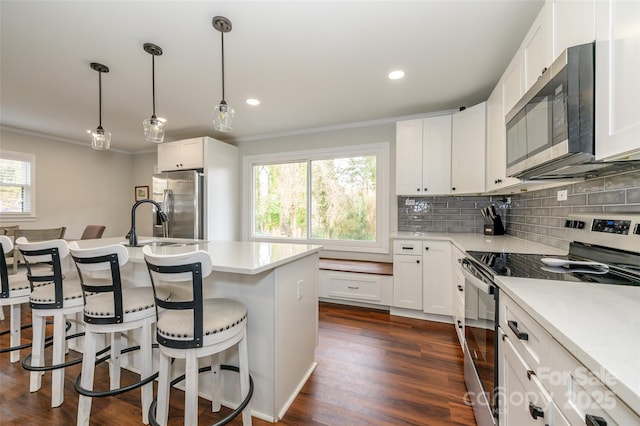 kitchen featuring a breakfast bar, decorative light fixtures, white cabinets, decorative backsplash, and stainless steel appliances