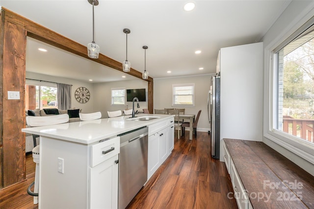 kitchen featuring dark wood-type flooring, a kitchen bar, pendant lighting, stainless steel appliances, and a kitchen island with sink