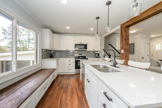 kitchen featuring white cabinetry, stainless steel appliances, sink, and a center island with sink