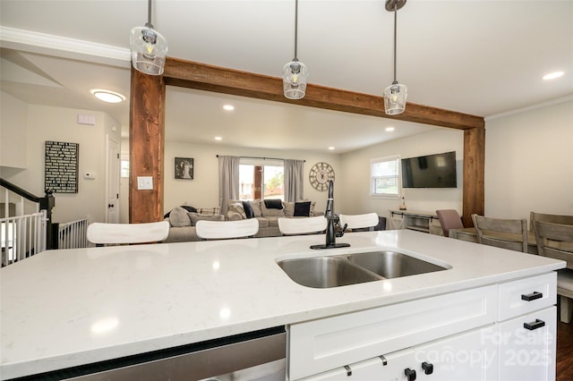 kitchen with sink, light stone counters, decorative light fixtures, beamed ceiling, and white cabinets