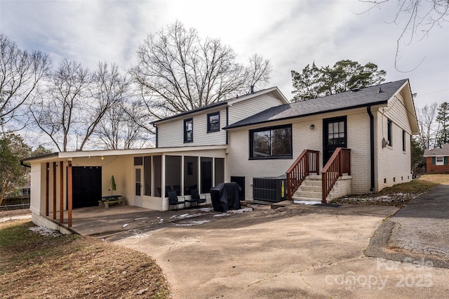 back of property featuring cooling unit, a sunroom, and a carport