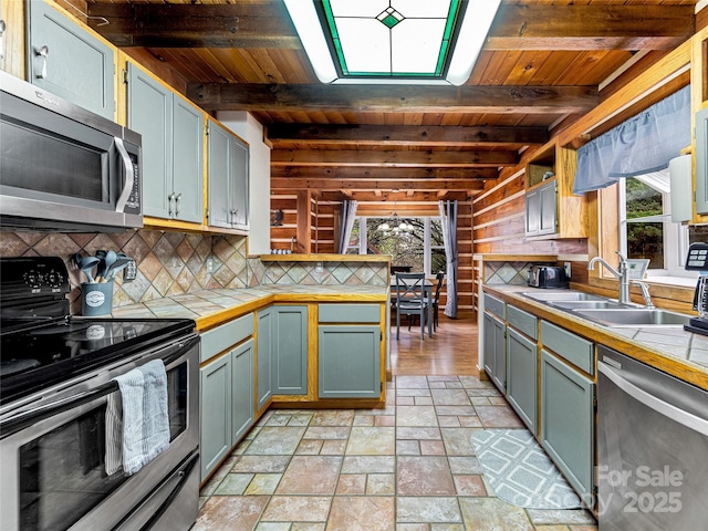 kitchen featuring beamed ceiling, wood ceiling, stainless steel appliances, and sink