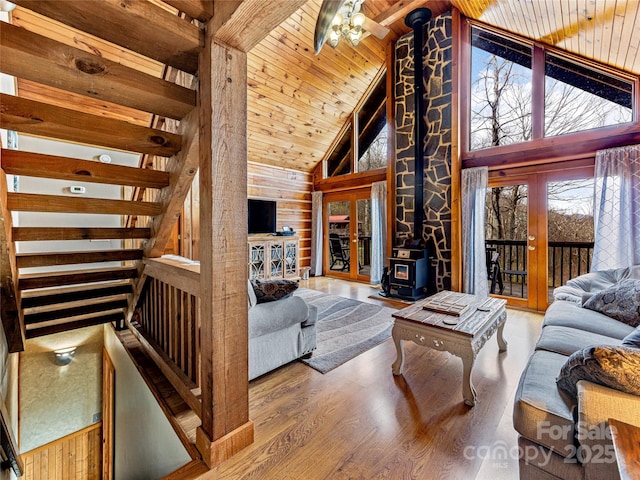 living room featuring wood ceiling, high vaulted ceiling, wood walls, and a wood stove