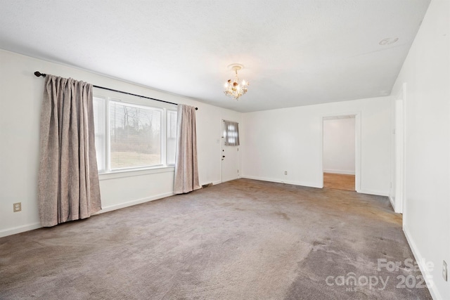 carpeted spare room with a chandelier