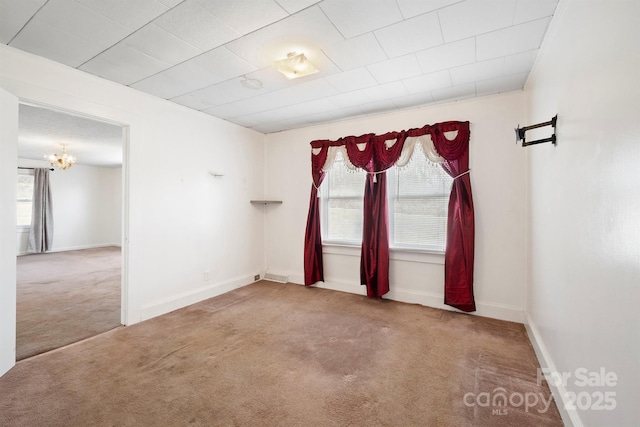 empty room with an inviting chandelier and carpet flooring