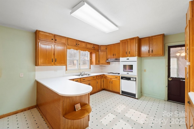 kitchen with sink, white appliances, and kitchen peninsula