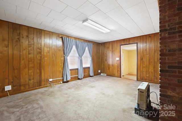 spare room with light carpet and wood walls