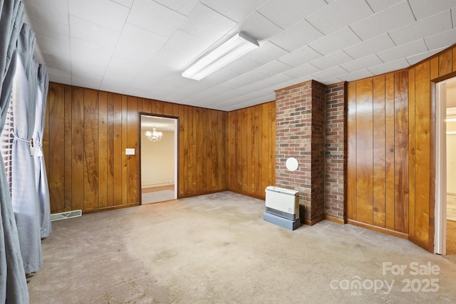 carpeted spare room featuring wood walls