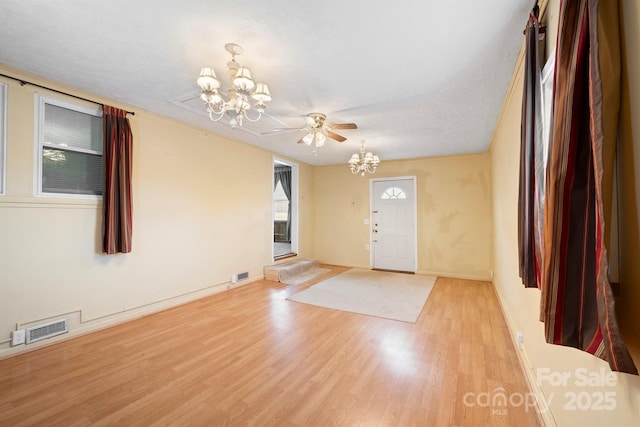 entryway with a textured ceiling, a notable chandelier, and light hardwood / wood-style floors