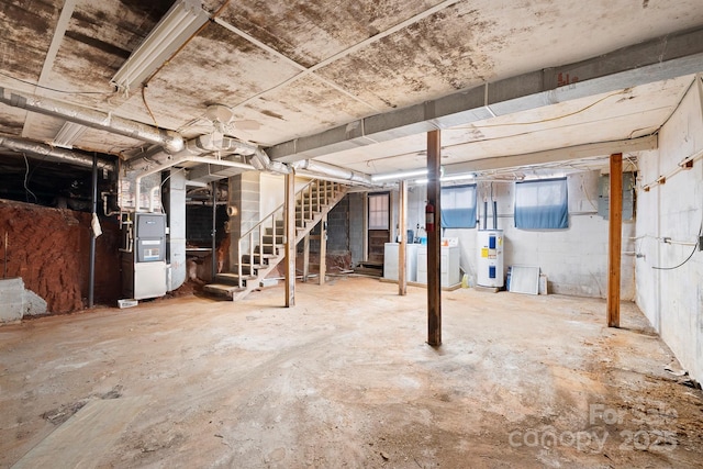 basement featuring washer and dryer, electric water heater, and heating unit