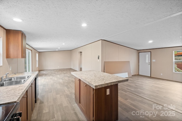 kitchen featuring a kitchen island, stove, sink, and light hardwood / wood-style flooring