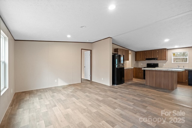 kitchen with a kitchen island, light hardwood / wood-style flooring, a textured ceiling, and black appliances