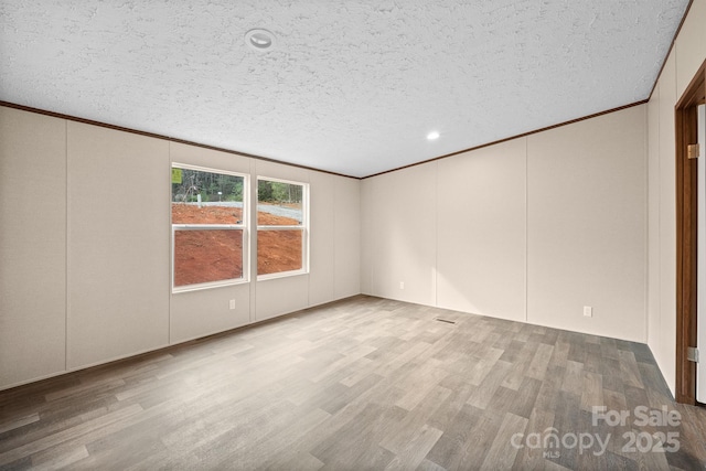 unfurnished room featuring ornamental molding, light hardwood / wood-style flooring, and a textured ceiling