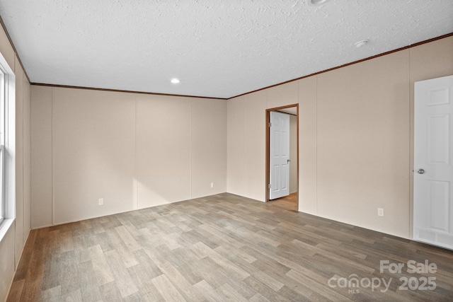 empty room featuring hardwood / wood-style flooring, crown molding, and a textured ceiling