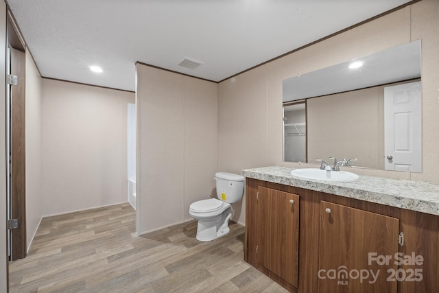 bathroom featuring hardwood / wood-style flooring, vanity, crown molding, and toilet