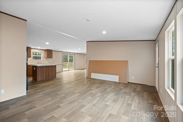 unfurnished living room featuring a textured ceiling and light hardwood / wood-style flooring