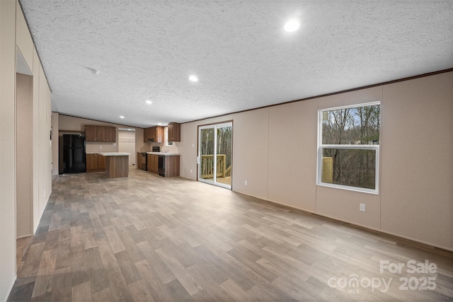 unfurnished living room featuring crown molding, a textured ceiling, and light wood-type flooring