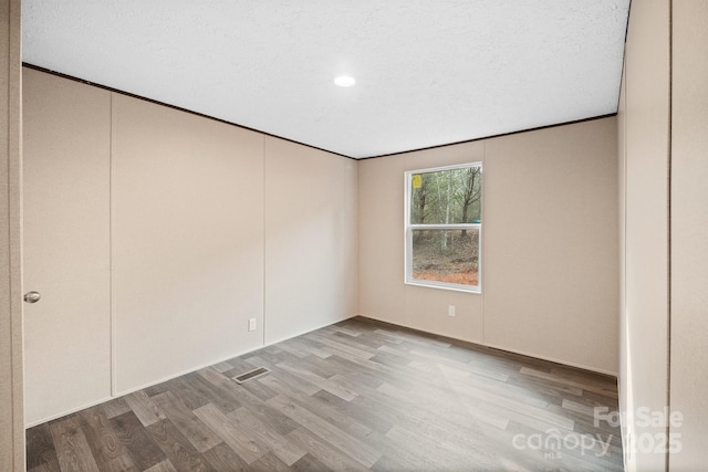 unfurnished room featuring crown molding, light hardwood / wood-style flooring, and a textured ceiling