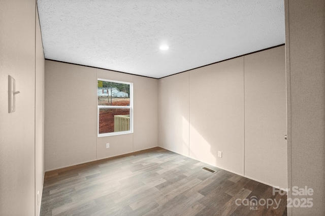 spare room featuring ornamental molding, a textured ceiling, and light wood-type flooring