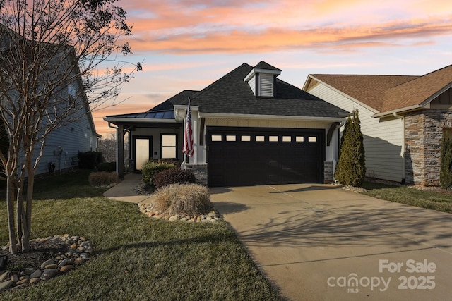 view of front of home with a garage and a lawn