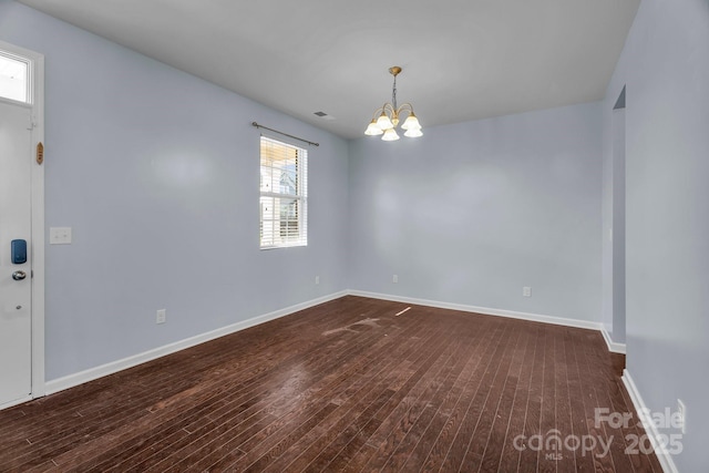 spare room with dark hardwood / wood-style floors and a chandelier