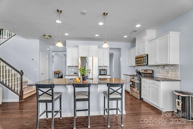 kitchen featuring hanging light fixtures, stainless steel appliances, and a center island with sink