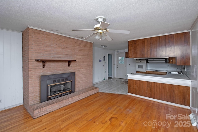 kitchen with range hood, oven, a textured ceiling, and wood walls